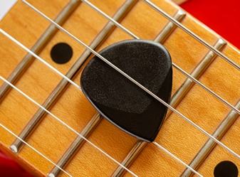 Photo of fretboard with a pick in the strings. Turn Your Fretboard Into a Map - The Visual Guitar Learning System for Any Key, Any Song